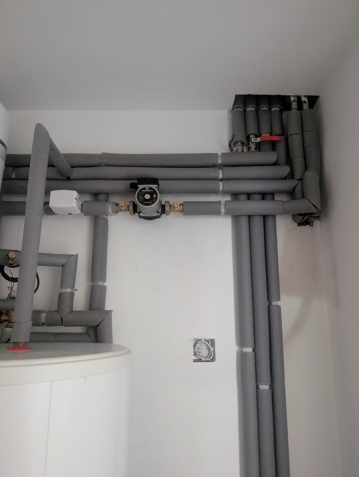Insulated heating pipework and circulating pump above the cylinder in Greenwich